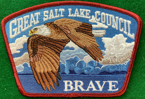 Great Salt Lake Council Friends of Scouting (FOS) Edition CSP SA-186:1. Embroidered Full Color Bald Eagle Flying Infront of Blue and White Cloudy Sky Background with 'Brave' Detail. Dark Red Border. Mint Condition.