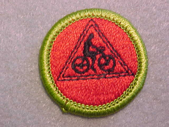 CYCLING- RED BACKGROUND, MERIT BADGE WITH CLEAR PLASTIC BACK, GREEN BORDER, NO IMPRINTS/LOGOS IN PLASTIC
