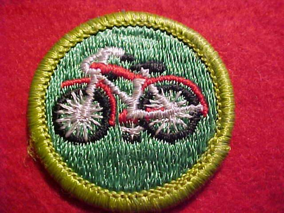 CYCLING, MERIT BADGE WITH CLEAR PLASTIC BACK, GREEN BORDER, NO IMPRINTS/LOGOS IN PLASTIC, GREEN BACKGROUND, 1972-74